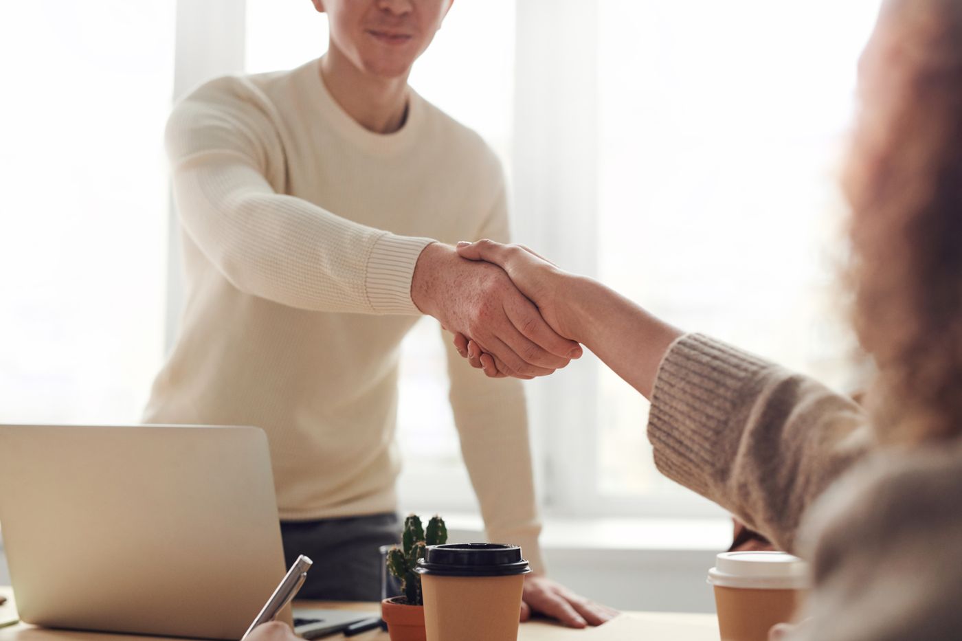 A professional handshake across a desk