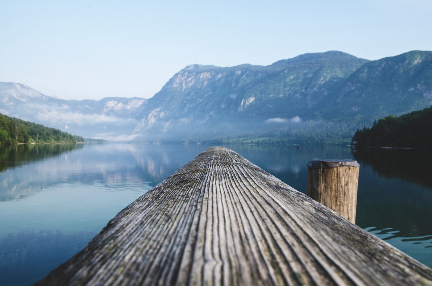 Timber boardwalk extending towards a mountain lake
